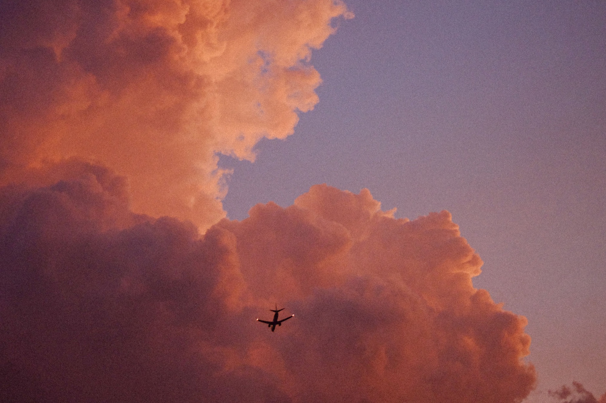 Avion dans un ciel de nuages roses au coucher du soleil