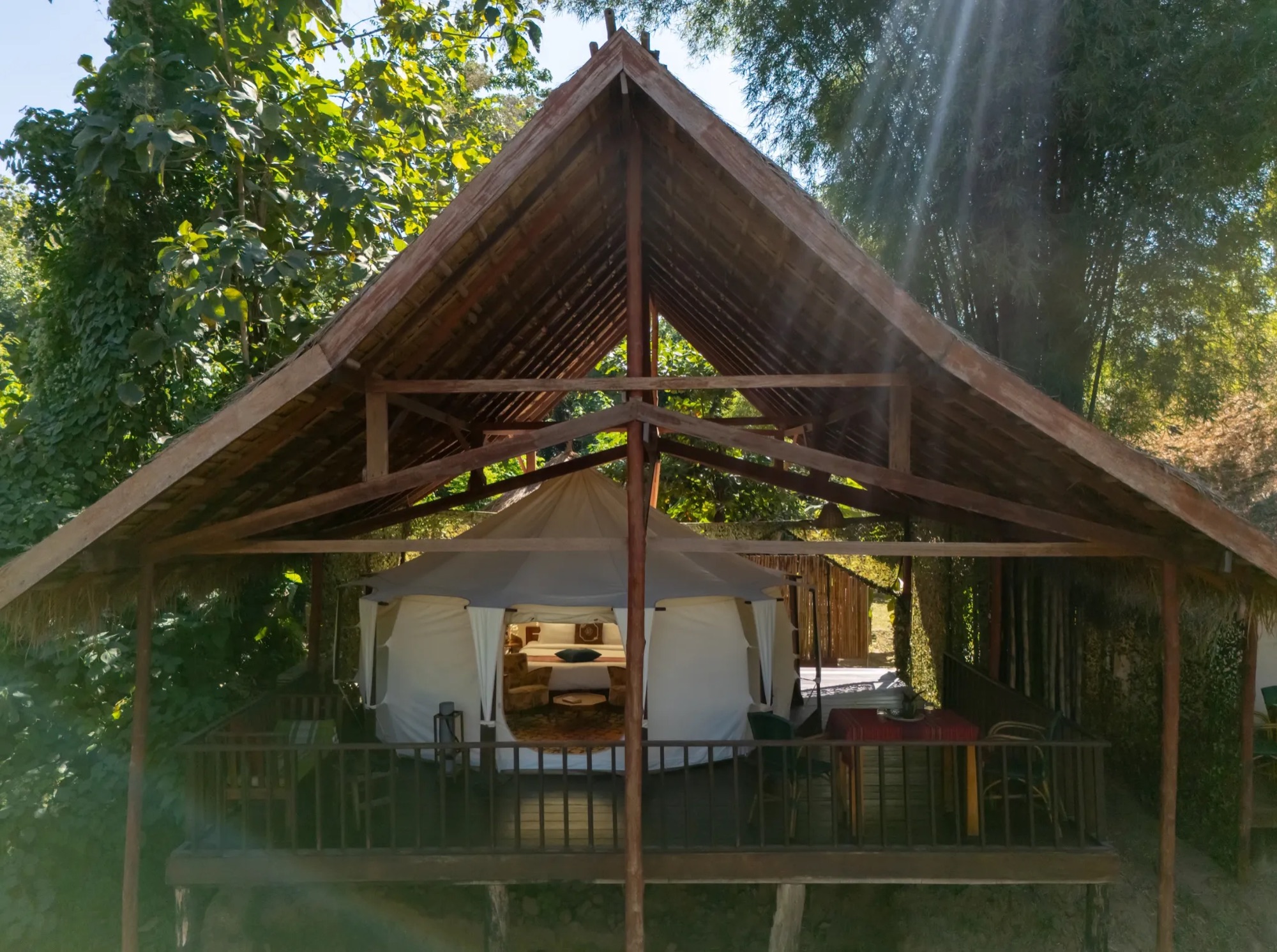 Tentes de glamping et villas sur les rives de la Nam Khan, végétation tropicale et lumière dorée matinale